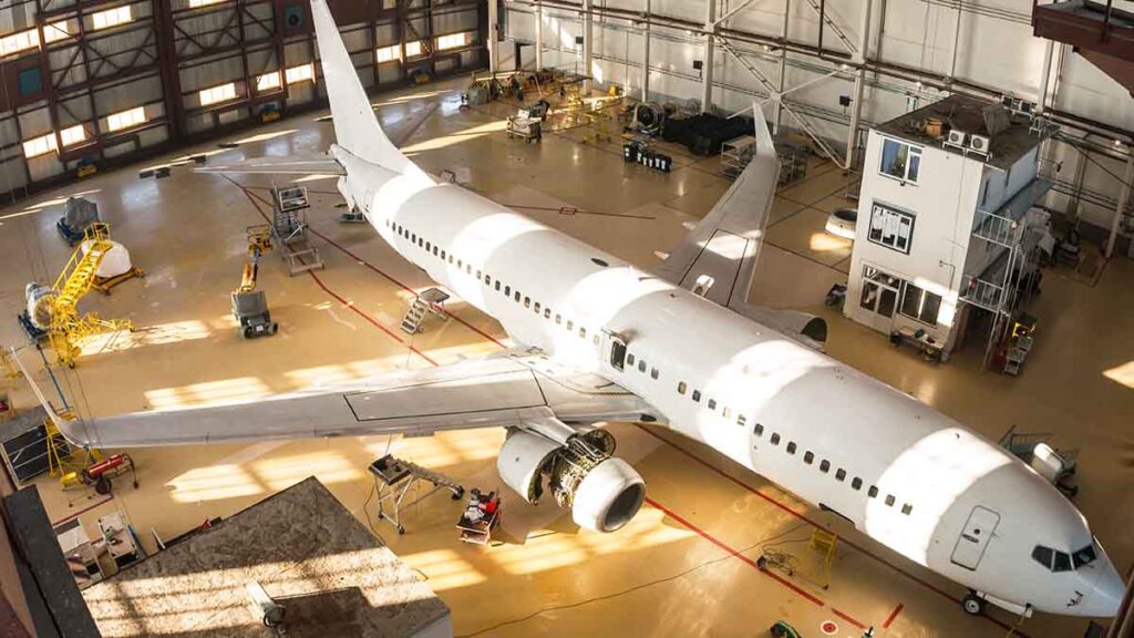 Aircraft sitting inside hangar undergoing heavy check maintenance.