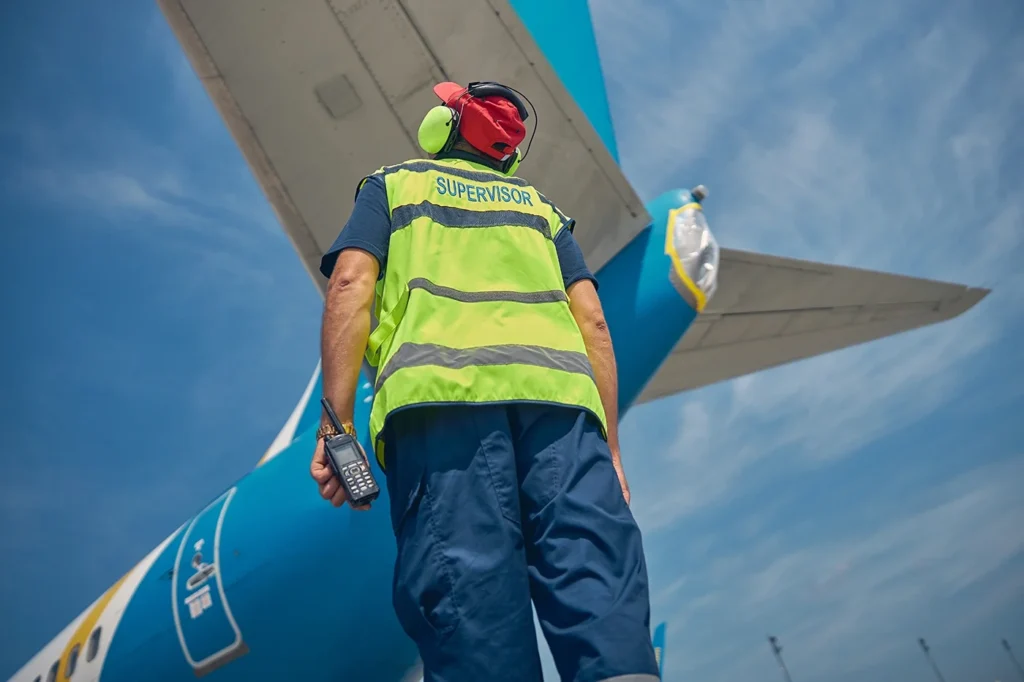 Supervisor on runway beneath airplane tail